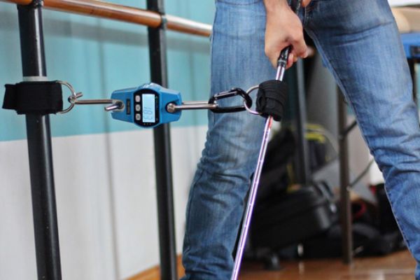 Hombre ejerciendo fuerza en un palo de golf atado a un medidor. 