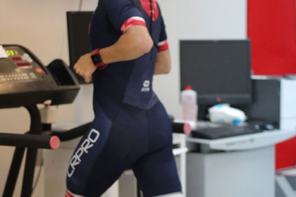 Atleta corriendo sobre una caminadora con instrumentos de medición en su cuerpo.